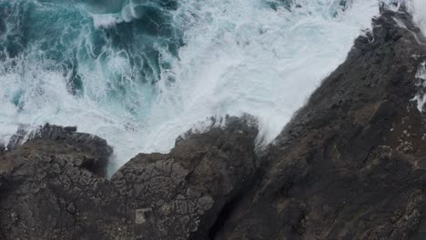 Aerial-Topdown-View-Of-Ocean-Waves-Splashing-Against-The-Rocky-Coast-Of-Vagar-Cliff-In-Faroe-Island,-Denmark