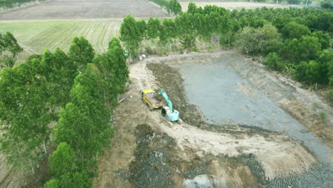 Aerial-drone-view-of-backhoe-machinery-digging-the-soil-to-load-a-dump-truck