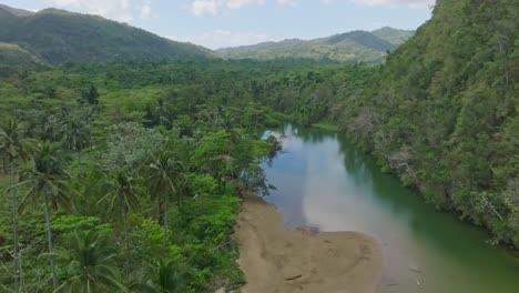 Drone-flying-over-Rio-San-Juan-surrounded-lush-and-tropical-vegetation,-Samana-in-Dominican-Republic