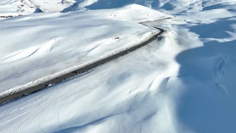 Wide-aerial-view-of-car-crossing-snowy-Vikafjell-Mountain-road,-Western-Norway
