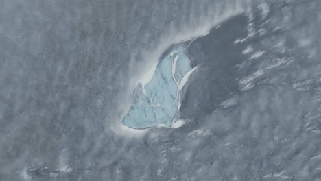 Iceberg-in-Frozen-Glacial-Lake,-Top-Down-Aerial-View,-HIghlands-of-Iceland