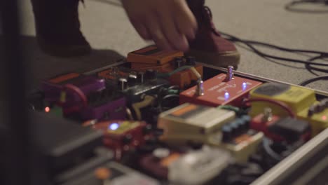 Person-checking-pedals,-switches-for-electric-guitars-during-concert-setup