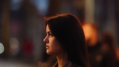 Close-up-of-profile-portrait-of-a-young-brunette-caucasian-woman-with-serious-expression-in-the-city-at-night
