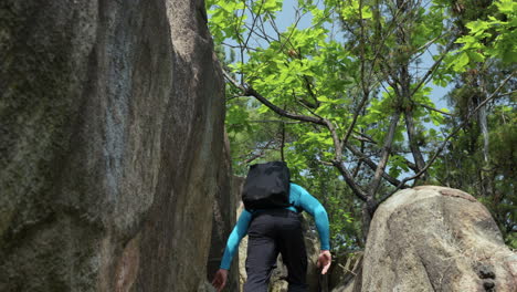 Confident-male-free-solo-climber-rock-climbing-in-Gwanaksan-Mountain-Forest---low-angle-rear-following-view-behind