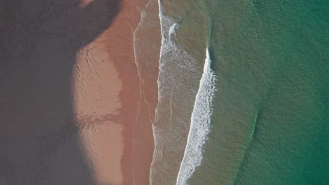 Top-Aerial-View-Of-Foam-Waves-Breaks-On-Orange-Colored-Sand-Beach