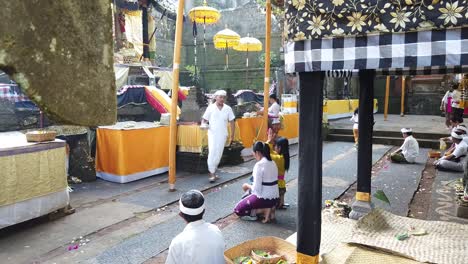 Asiatische-Frauen-Beten-Im-Balinesischen-Hindu-Tempel,-Priester-Gießt-Weihwasser-In-Gläubige,-Natürliche-Atmosphäre-Im-Spirituellen-Bali,-Indonesien