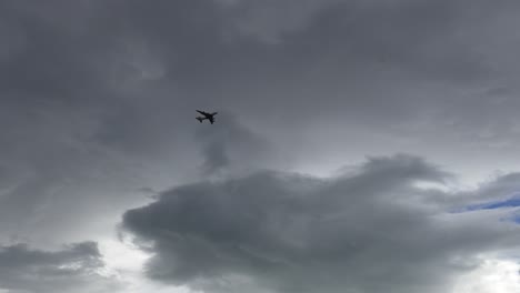 Panning-slowly-to-follow-aircraft-as-it-passes-underneath-grey-cumulus-clouds---Canterbury,-New-Zealand