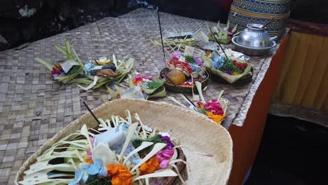 Sage-and-Religious-Vessels-Displayed-in-Bali-Temple-Ceremony,-Colorful-Flowers-and-Coconut-Baskets-for-Praying-Ritual
