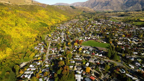 Colourful-autumn-forest-by-historic-gold-mining-town-Arrowtown,-New-Zealand,-aerial-view