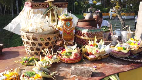 Ancient-Shamanic-Priest-Dressed-in-White-Displays-Ritual-Offerings-Sage-and-Incense-with-Colorful-Flowers-in-Balinese-Hindu-Temple,-Indonesia