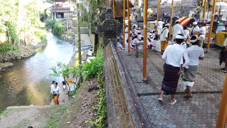 Hindu-Balinese-People-Pray-in-Temple-Next-to-River-and-Forest-Religious-Ceremony-at-Bali-Indonesia-Outdoors,-Pura-Samuan-Tiga