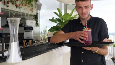 Black-Clad-Server-at-Bar-Taking-Red-Fruit-Cocktail-onto-Tray