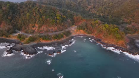 Aerial-cinematic-shot-approaching-a-traffic-road-parallel-to-the-beach-coast-at-dusk,-Costa-Rica
