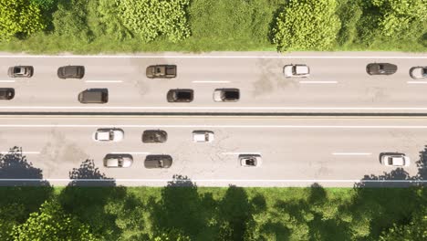 Highway-with-two-lanes-in-both-directions,-inside-a-forest,-with-cars-passing-by-3D-animation-top-view-zoom-out