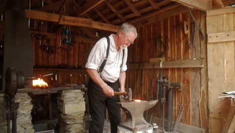 Un-Recreador-De-Herrero-Da-Vida-A-La-Historia-Al-Retratar-A-Un-Herrero-Tradicional,-Mostrando-El-Arte-Y-El-Comercio-Del-Trabajo-Del-Metal-Con-Herramientas-Y-Métodos-Auténticos.