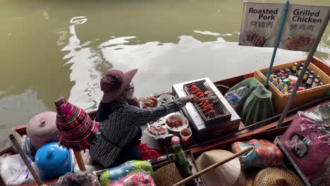 Vendors'-grilled-skewers-on-the-boat-in-Damnoen-Saduak-Floating-Market,-Ratchaburi-province,-South-West-of-Bangkok,-Thailand