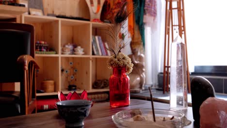 Burning-Incense-on-a-Wooden-Table-in-a-Spiritual-Cabinet,-with-Religious-Objects-and-Books-in-the-Background