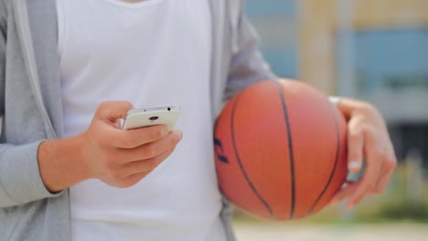 Man-with-a-basketball-holding-a-smartphone---close-up