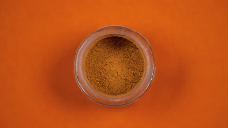 A-glass-of-orange-chili-pepper-powder,-on-a-rotating-surface