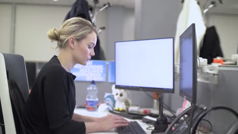Blonde-female-employee-is-working-on-a-computer-with-two-screens