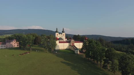 Drone-shot-of-Czech-countryside-with-monastery-on-top-of-the-hill-during-sunset