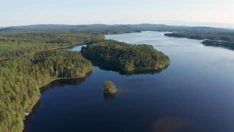 Panoramic-drone-shot-of-crystal-clear-lake-in-Sweden-inland-surrounded-by-deep-forest-landscape