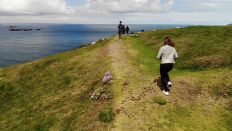 A-group-of-young-people-hiking-in-Ireland,-Coastal-scenery