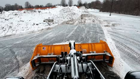 POV-Eines-Bulldozers,-Der-Schnee-In-Einen-Haufen-Pflügt,-Um-Die-Straße-Nach-Einem-Schneesturm-Freizumachen