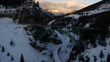Aerial-Cinematic-drone-Vail-Avon-Red-Cliff-Iconic-Bridge-in-Colorado-mid-winter-late-sunset-backward-movement-pan-up