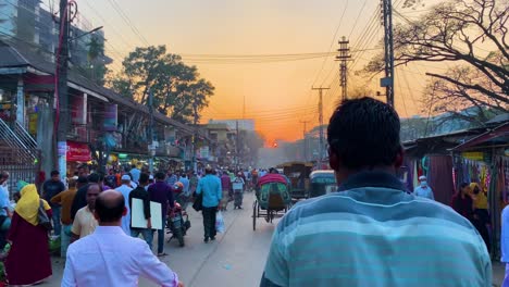 In-a-busy-street-in-Bangladesh-at-sunset,-a-rickshaw-puller-is-pulling-the-rickshaw,-and-the-sunset-is-in-the-foreground-in-Sylhet,-Bangladesh