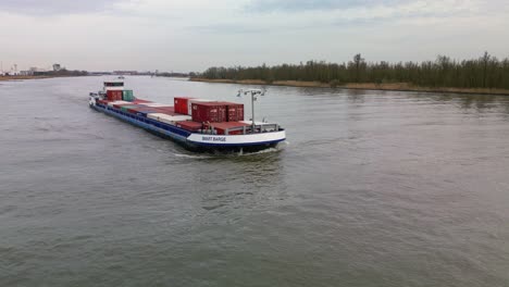 Small-industrial-cargo-ship-navigating-through-the-canal-on-a-cloudy-day