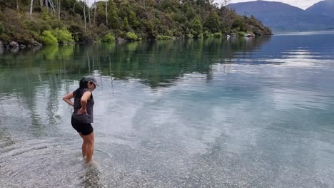 Latin-woman-Wading-into-cold-water-on-the-bobs-cove-walk-in-lake-wakatipu