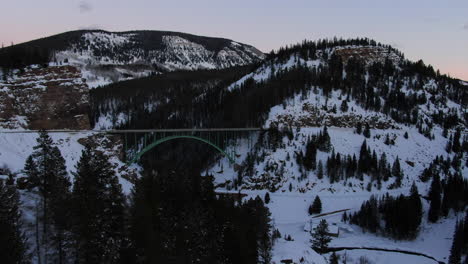 Aerial-Cinematic-drone-Vail-Avon-Red-Cliff-Iconic-Colorado-Bridge-mid-winter-late-sunset-cars-driving-past-pan-up-reveal-forward-movement