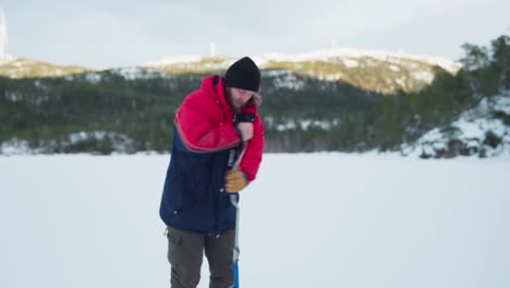 An-Ice-Fisherman-With-A-Hand-Auger-Drilling-A-Hole-In-Frozen-Lake