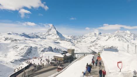Turistas-En-La-Estación-De-Tren-Cremallera-De-Gornergrat-En-La-Cima-De-La-Estación-De-Esquí-De-Zermatt-Con-Panorama-Montañoso-Y-El-Pico-Matterhorn-En-Invierno