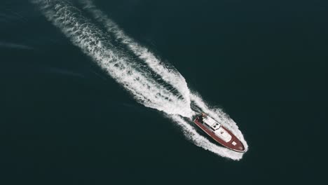 Aerial-Tracking-Shot-of-Small-Speed-Boat-Speeding-Away-in-Blue-Ocean-Water,-Tenerife-Spain