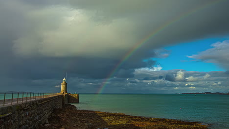 Lighthouse-overlooking-sea-with-storm-clouds-and-rainbow-in-background