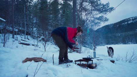 Mann-Mit-Metallgrillständer-Kocht-Außerhalb-Der-Winterlandschaft