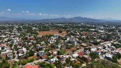 Drone-shot-rising-over-the-townscape-of-Puerto-Escondido,-in-sunny-Oaxaca,-Mexico