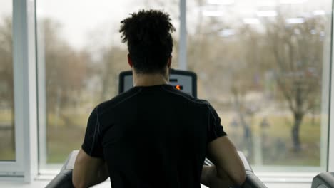 Man-trains-in-gym-doing-cardio-workout-on-treadmill,-back-view