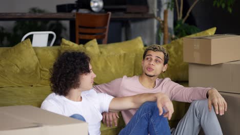Homosexual-couple-talking-in-a-new-apartment-around-boxes