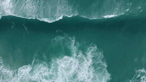 Aerial-View-Of-Foamy-Waves-Coming-Onto-The-Beach-In-Nazare,-Portugal