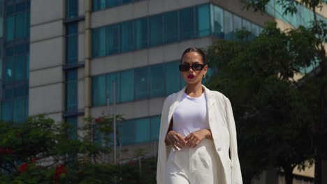A-latina-female-donning-a-professional-outfit-striding-through-the-urban-landscape-with-towering-skyscrapers-as-the-backdrop