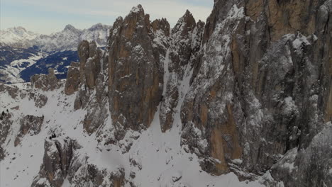 Aufsteigende-Luftaufnahme-Des-Schneebedeckten-Berggipfels-Des-Putiakofels-Mit-Epischer-Enthüllung-Der-Landschaft-Im-Hintergrund