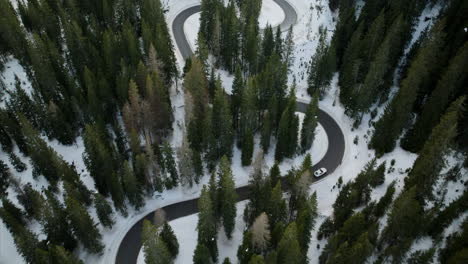 Luftaufnahme-Eines-Autos,-Das-Durch-Den-Schneebedeckten-Giau-Pass-Durch-Den-Alpenwald-Fährt