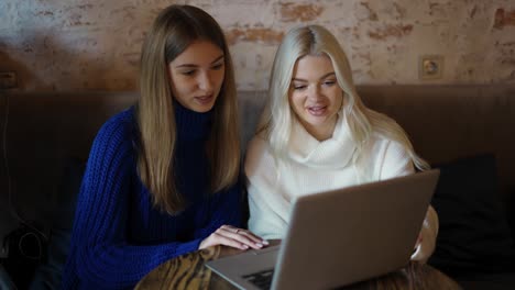 Two-pretty-girls-having-a-meeting-at-a-modern-cafe,-using-laptop-and-discussing-topic