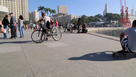 People-sitting-down,-relaxing,-on-bikes,-in-front-of-Museu-do-Amanha,-Tomorrow's-museum,-at-Praca-Maua,-in-the-center-of-Rio-de-Janeiro,-Brazil,-on-a-Sunday-afternoon