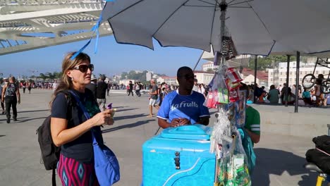 Woman-buying-ice-cream,-in-front-of-Museu-do-Amanha,-Tomorrow's-museum,-at-Praca-Maua,-in-Rio-de-Janeiro,-Brazil