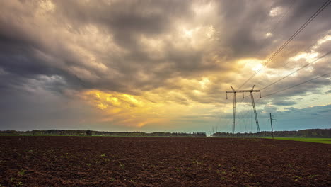 Clouds-moving-fast-at-sunset-over-electrical-tower-in-countryside