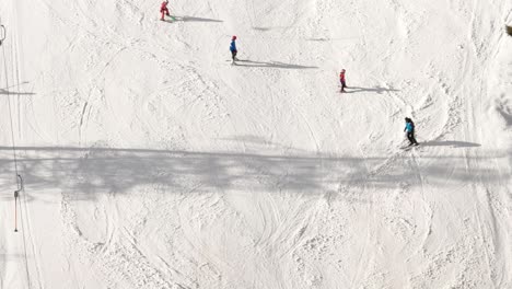 Aerial-view-of-skiers-going-up-by-skilift-or-ski-lift-and-instructor-teaching-kids-how-to-ski-on-snow-in-winter